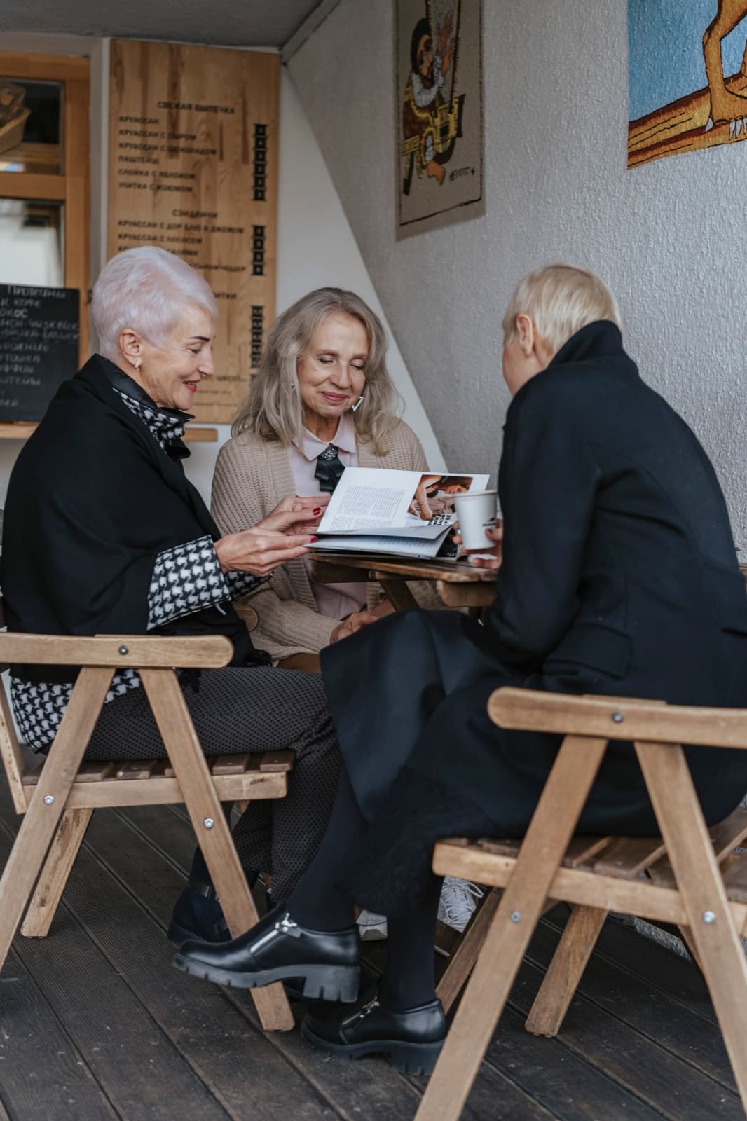Three people sit talking at a table in a cafe